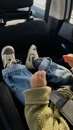 a child sitting in the back seat of a car with their feet up on someone's lap