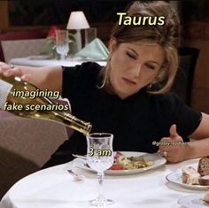 a woman sitting at a table with food and wine in front of her, that says taurus imagine fake scenarios