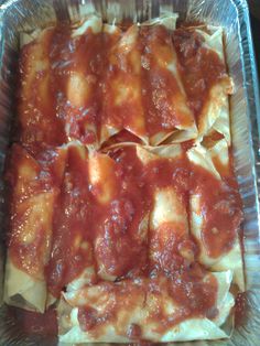 a pan filled with ravioli covered in marinara sauce on top of aluminum foil