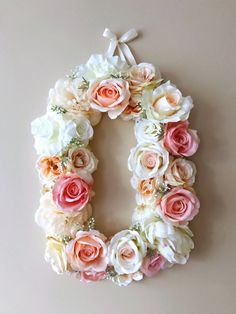 the letter o is made up of flowers and ribbons on a white wall with a bow