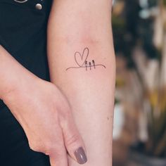 a woman's arm with two birds and a heart tattoo on the left forearm