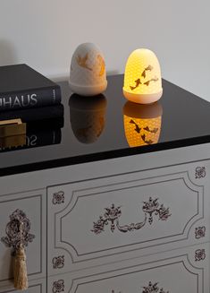 an egg sitting on top of a black table next to a white dresser with books