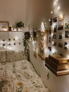 a bedroom with plants and pictures on the wall above the bed, along with hanging lights