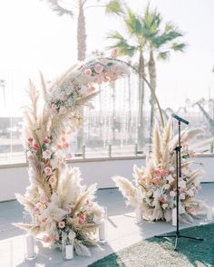 an outdoor ceremony setup with flowers and pamonini on the ground, near a microphone