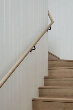 there is a wooden hand rail on the stair treads in this house with white walls and wood flooring