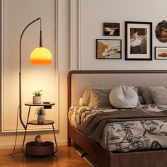 a bed room with a neatly made bed next to a night stand and pictures on the wall