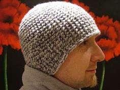 a close up of a person wearing a knitted hat with flowers in the background