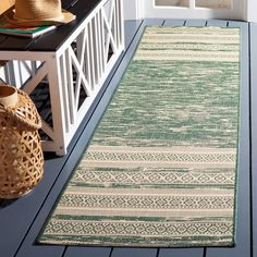 a green and white rug sitting on top of a wooden floor next to a bench