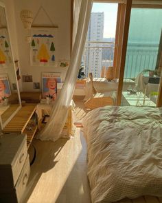 a bedroom with a bed, dresser and window overlooking the ocean in front of it