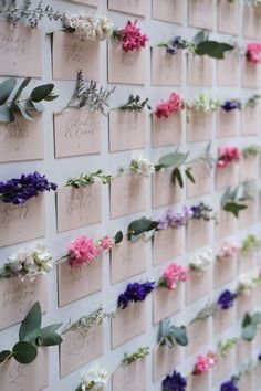 flowers are arranged on the side of a wall with cards attached to it that spell out names