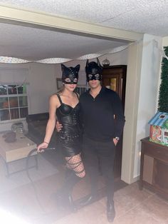 a man and woman dressed up in catwoman costumes posing for a photo with each other