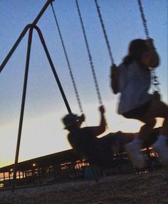 two people swinging on swings at sunset