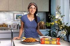 a woman standing in front of a plate of food on a kitchen counter next to a bag of chips