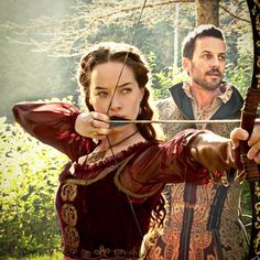 a man and woman dressed in medieval clothing aiming at an arrow