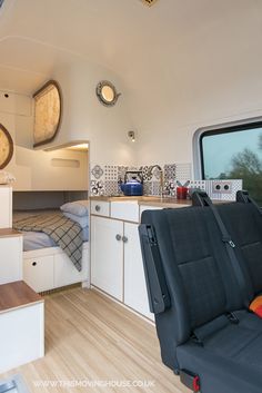 the interior of a camper with wood floors and white walls