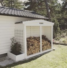 a small white shed with logs in it