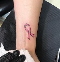 a small pink ribbon tattoo on the wrist for someone who is sick and needs to wear it