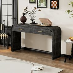 a black console table with two vases and a book on it in a living room