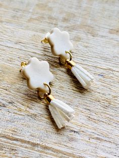 two white flowers with tassels are hanging from gold - plated ear wires