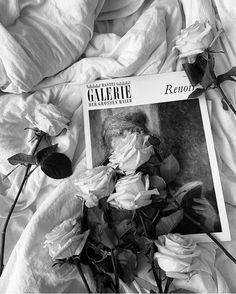 black and white photograph of roses on a bed with the cover pulled back over it