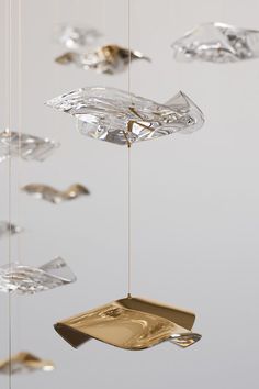 several pieces of glass hanging from strings in the shape of fish ornament, with gold plating