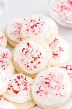 several cookies with white frosting and red sprinkles are on a plate