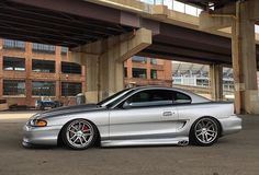 a silver sports car parked under an overpass