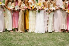 a group of women standing next to each other in long dresses holding bouquets and flowers