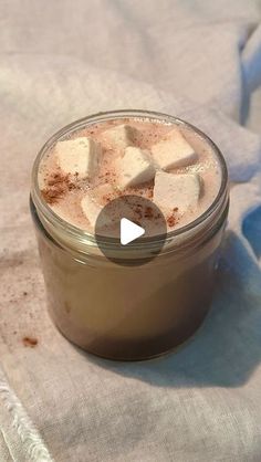 a glass jar filled with marshmallows sitting on top of a white cloth