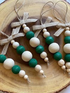 some green and white beads are on a wooden plate with twine bow ties around them