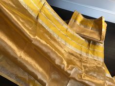 This is a beautiful handloom tissue silk organza saree in tissue gold/ mustard yellow with katan silk banarasi borders on either side. Saree has thin horizontal lines across the body and pallu. Saree in finished with yellow colour and tissue gold colour tassels. Saree comes with an unstitched blouse piece similar to the saree. Saree truly shimmers like gold and it is perfect to wear for an outdoor daytime wedding or an evening wedding. Falls and pico are done! All sales are final. Dry clean only. Rekha Saree, Alia Bhatt Saree, Saree Yellow, Tassels Saree, Daytime Wedding, Organza Silk Saree, Tissue Saree, Banarasi Silk Saree, Saree Border