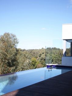 an empty swimming pool on the side of a house with trees in the background and blue sky