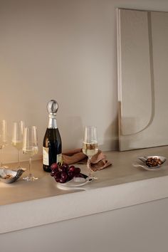 a table topped with wine glasses and plates filled with food next to a bottle of wine