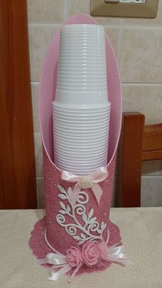 a stack of pink and white plates sitting on top of a wooden table next to a cup holder