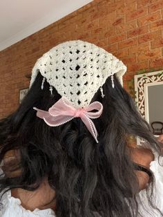 the back of a woman's head wearing a crocheted hat with pink ribbon