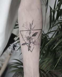 a black and white photo of a flower tattoo on the left leg with an inverted triangle behind it