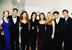 a group of people standing next to each other in formal wear posing for a photo