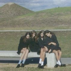 three young women sitting on a cement bench