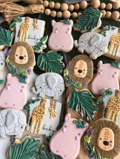 decorated cookies with jungle animals and giraffes are displayed on a table next to tassels