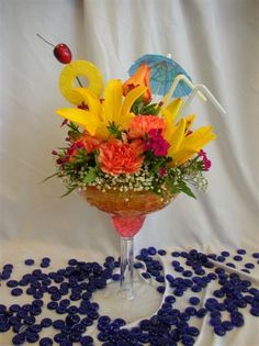 a vase filled with lots of colorful flowers on top of a blue table cloth next to an umbrella