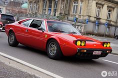 a red sports car is driving down the street