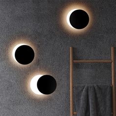 three circular lights are on the wall above a towel rack