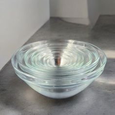 three glass bowls stacked on top of each other in front of a white wall and floor