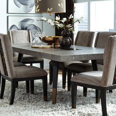 a dining room table with chairs and a vase on top of it in front of a window