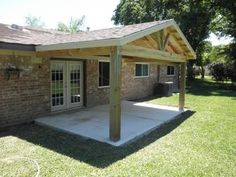 a covered patio in front of a brick house