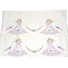 two white bedspreads with embroidered angels on them