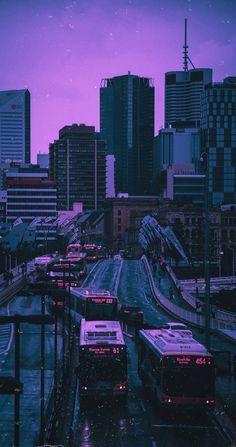 a city street filled with lots of traffic next to tall buildings under a purple sky