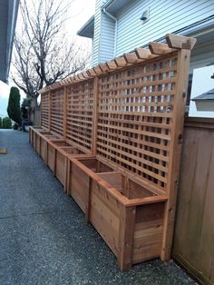 a row of wooden planters sitting on the side of a road next to a house