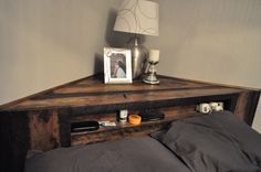 a bed sitting next to a night stand on top of a wooden table