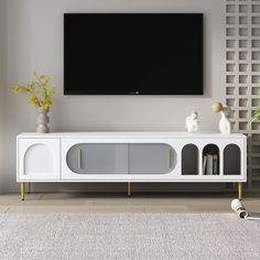 a white entertainment center with a flat screen tv mounted on it's sideboard